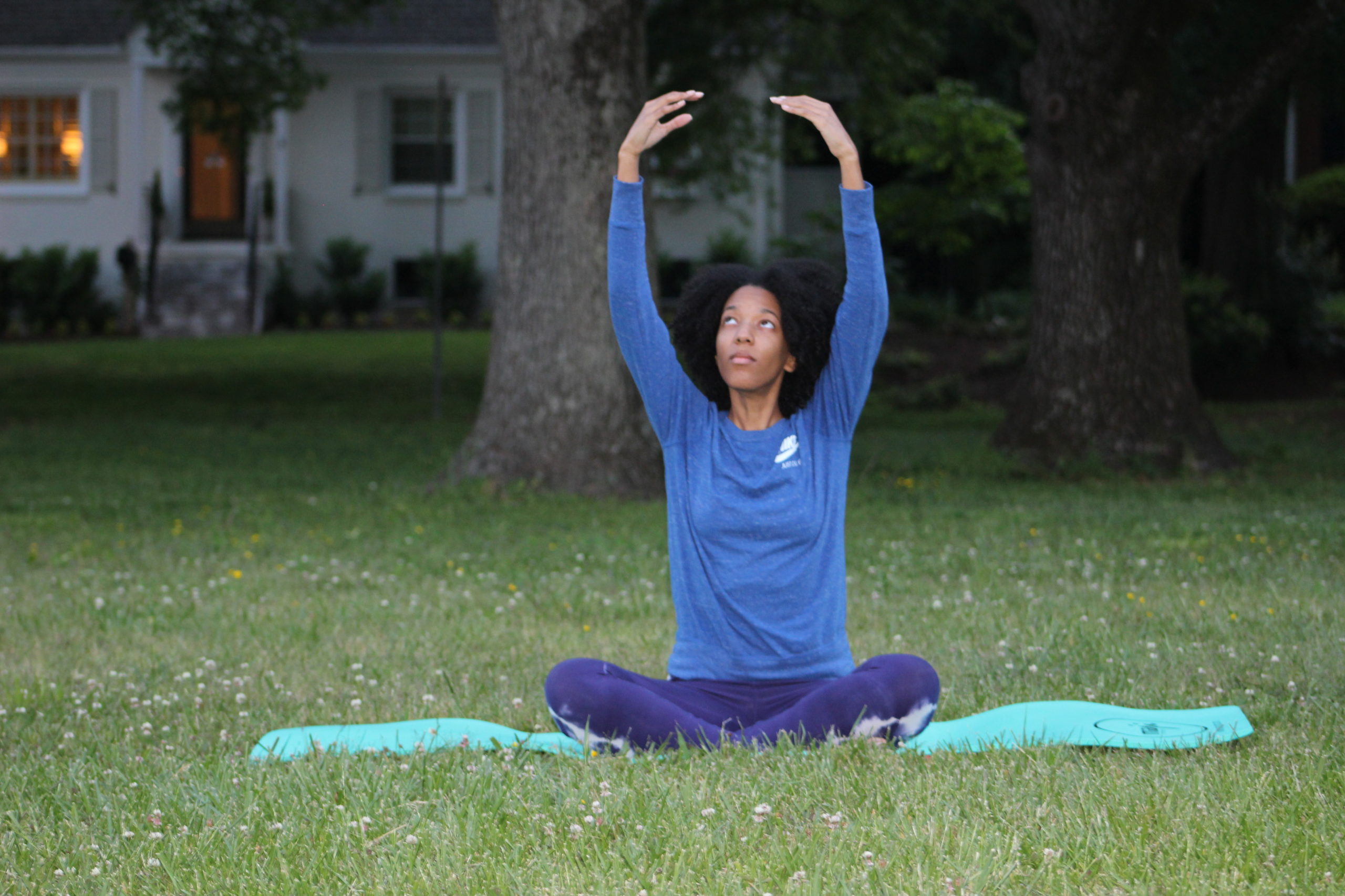 Melly doing a seated yoga pose in the grass